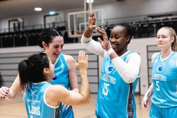 Caledonia Gladiators players celebrating on the basketball court after a win.
